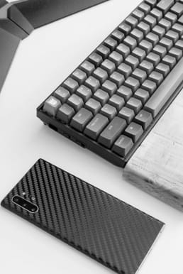 Black keyboard and a black phone on a white desk